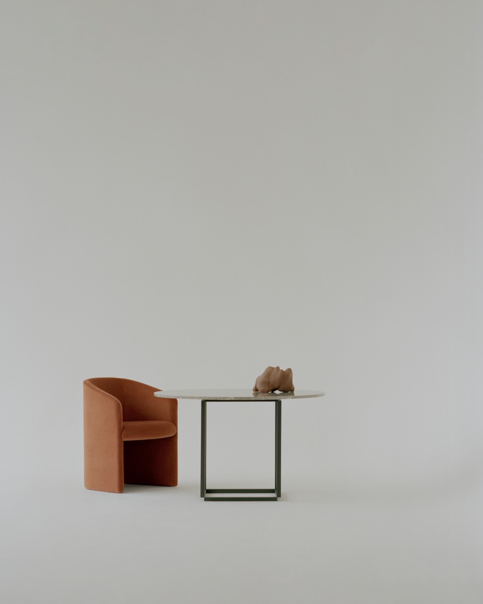 Covent Club Chair Sessel von New Works in Orange neben einem runden Tisch.
