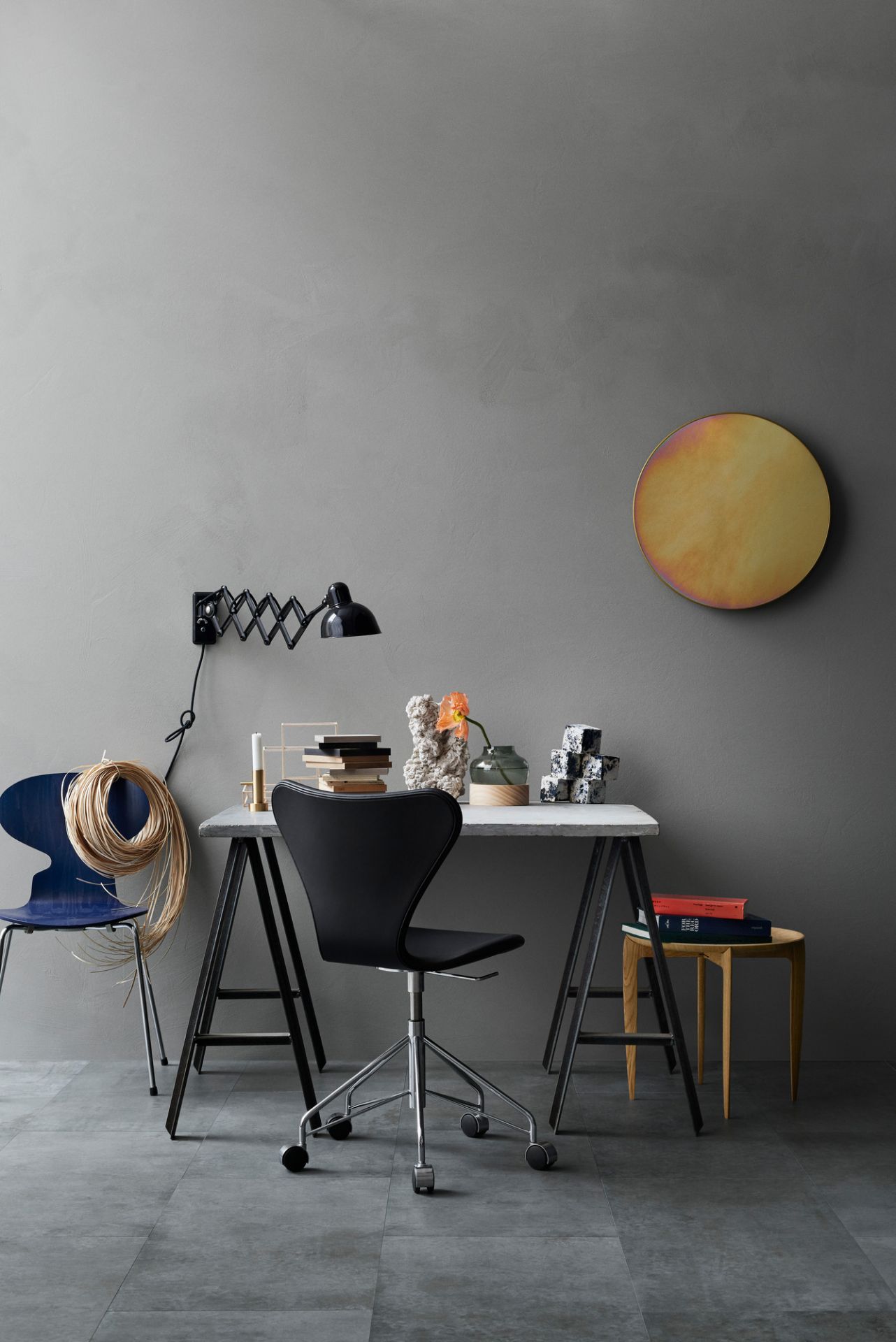 Moderner Arbeitsplatz mit Schreibtisch, Bürostuhl, Lampe und Deko-Elementen in Grau- und Blautönen.