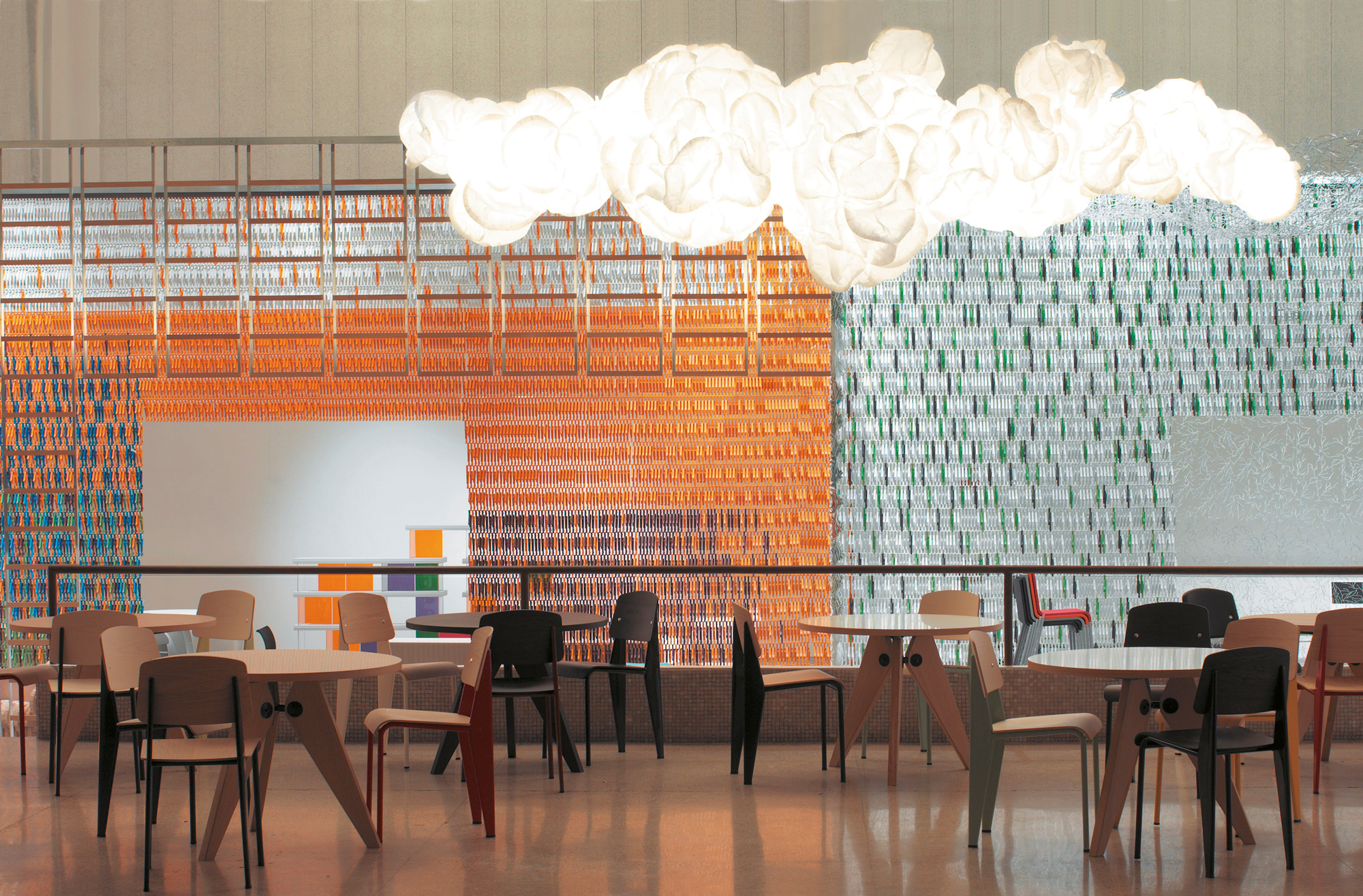Mamacloud Pendelleuchte von Belux: Wolkenförmige LED-Lampe in einem modernen Raum mit Tischen und Stühlen.