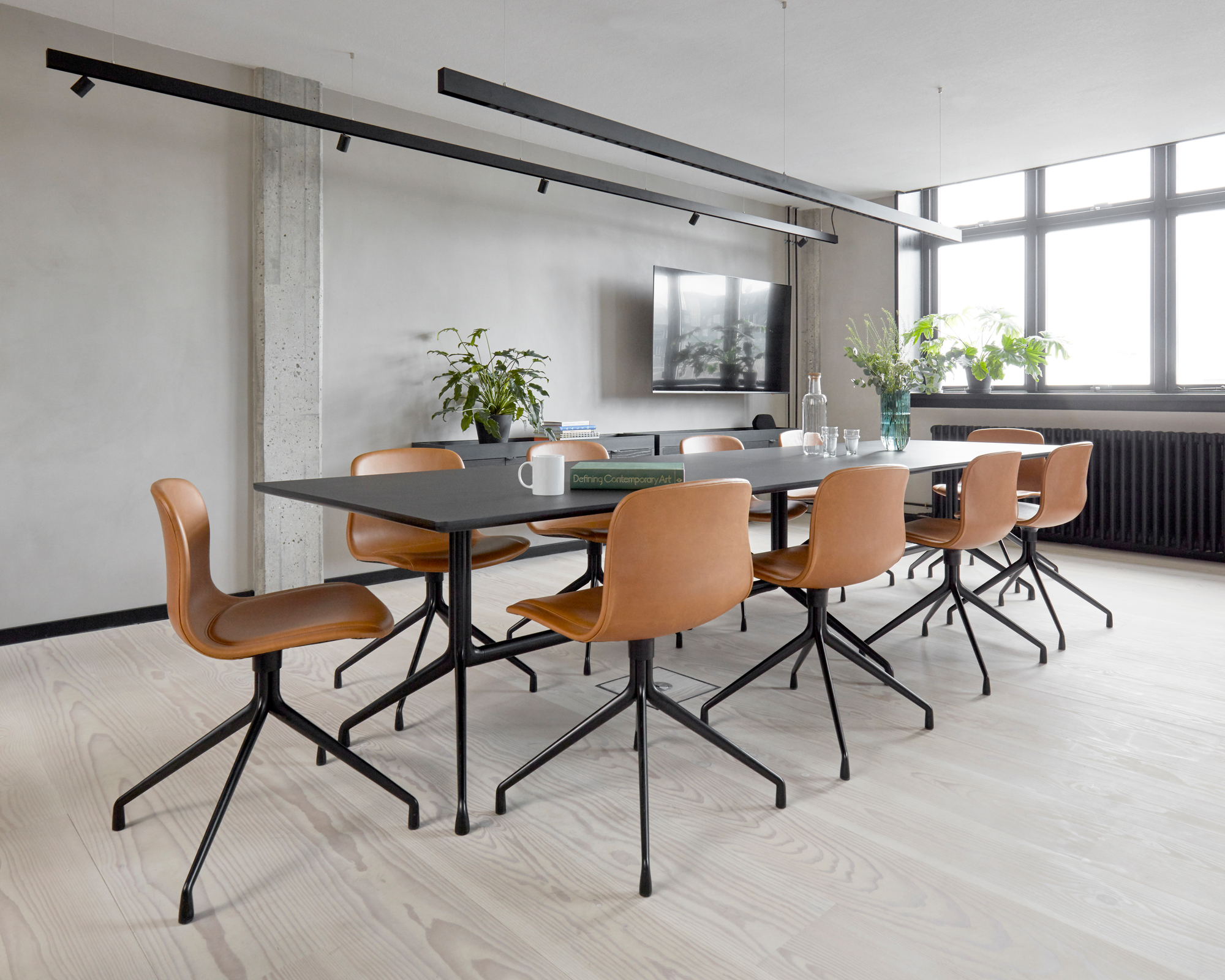 Konferenzraum mit schwarzem Tisch und braunen About a Chair AAC 11 Stühlen mit HALLINGDAL 173 Vollpolsterung.