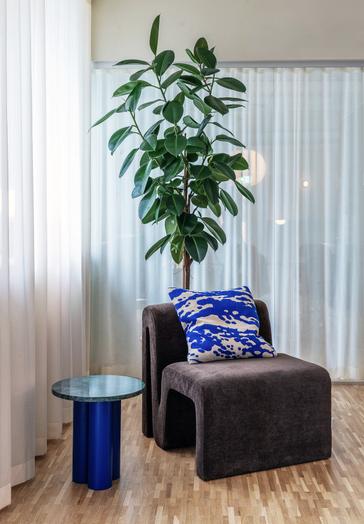 Normann Copenhagen Dit Coffee Table Beistelltisch in blau mit Pflanze und Sessel im modernen Wohnzimmer.