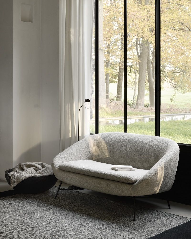 Barrow Sofa 2-Sitzer in Off-White vor Fenster mit Blick in die Natur, minimalistisches Wohnzimmer Design.