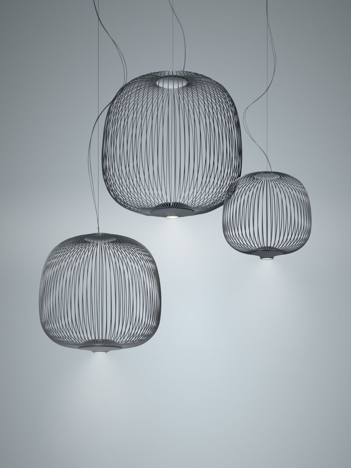 Drei schwarze Spokes Pendelleuchten von Foscarini mit filigranem Design und warmem Licht.