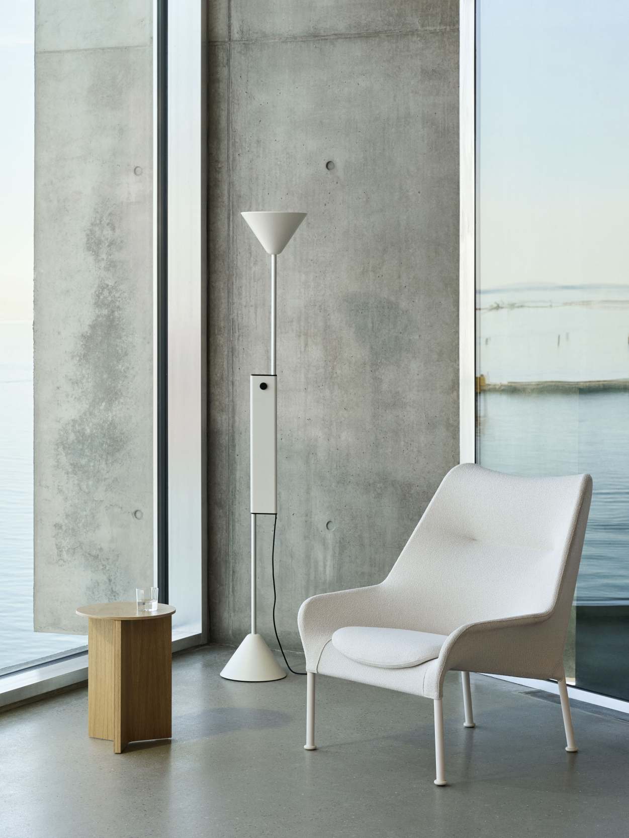 Weißer Hay 02 Lounge Chair Sessel mit passendem Beistelltisch und Stehlampe vor Betonwand und Fenster.