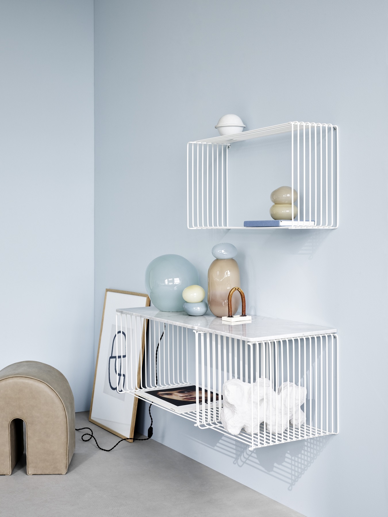 Weißes Panton Wire Regalsystem von Montana, erweiterbar, mit Deko-Objekten an hellblauer Wand.