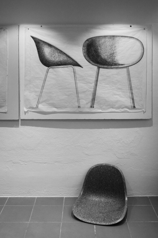 Schwarz-Weiß-Foto: Normann Copenhagen Mat Chair Holz Stuhl und Skizzen von Stühlen an der Wand.