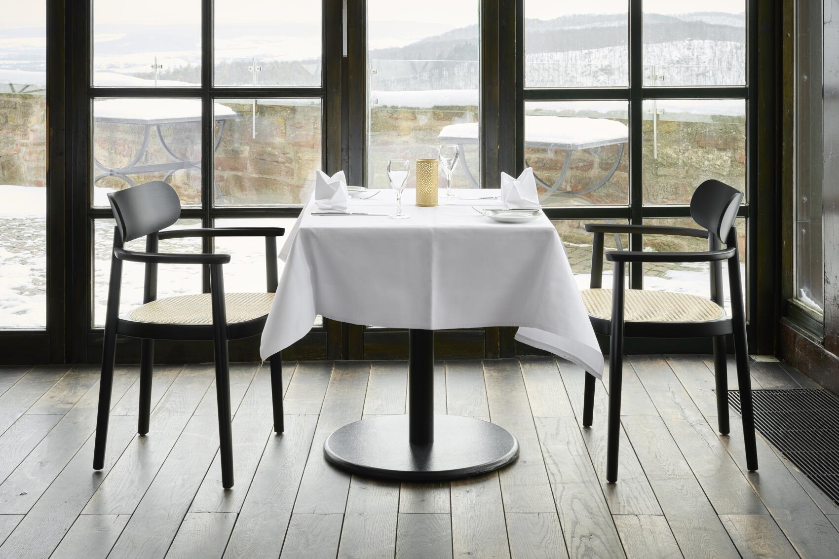 Schwarzer 118 FV Holzstuhl mit Armlehnen von Thonet an gedecktem Tisch in elegantem Restaurant.