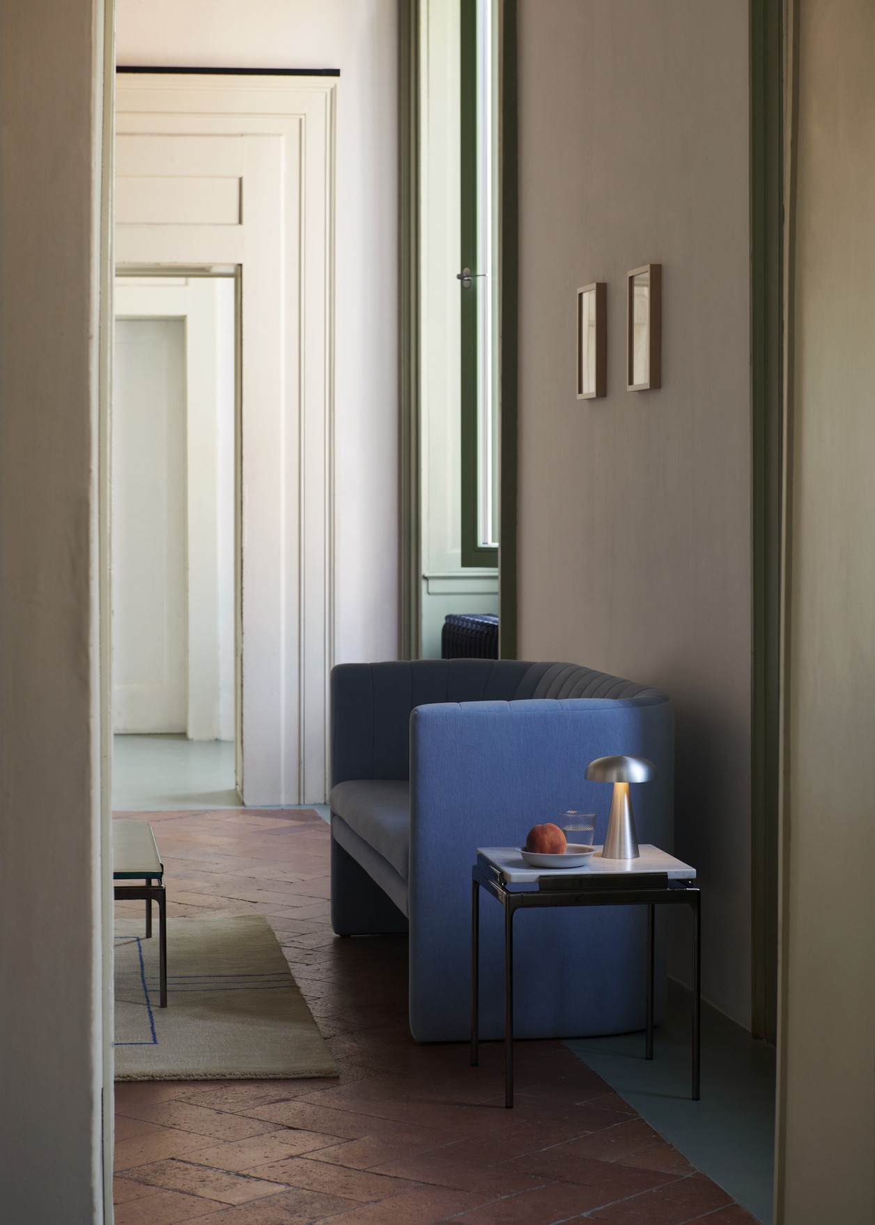 AndTradition Sett LN11 Beistelltisch mit Marmorplatte und Lampe neben blauem Sofa in stilvollem Interieur.