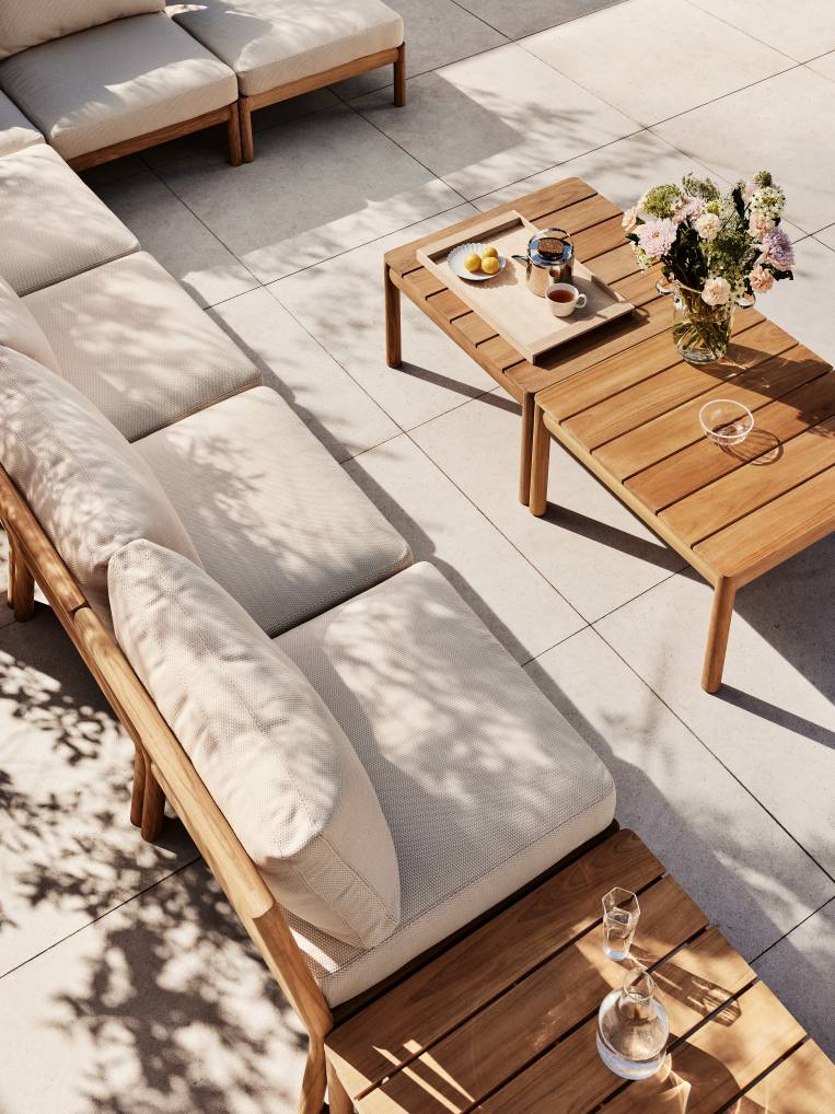 Draufsicht: Skagerak Tradition Lounge Tisch aus Teakholz neben modularem Sofa mit hellen Polstern.