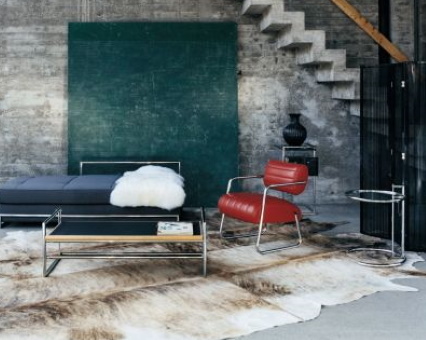 Bild von modernem Wohnzimmer mit Sofa, Sessel, Couchtisch und Kuhfellteppich im industriellen Stil.