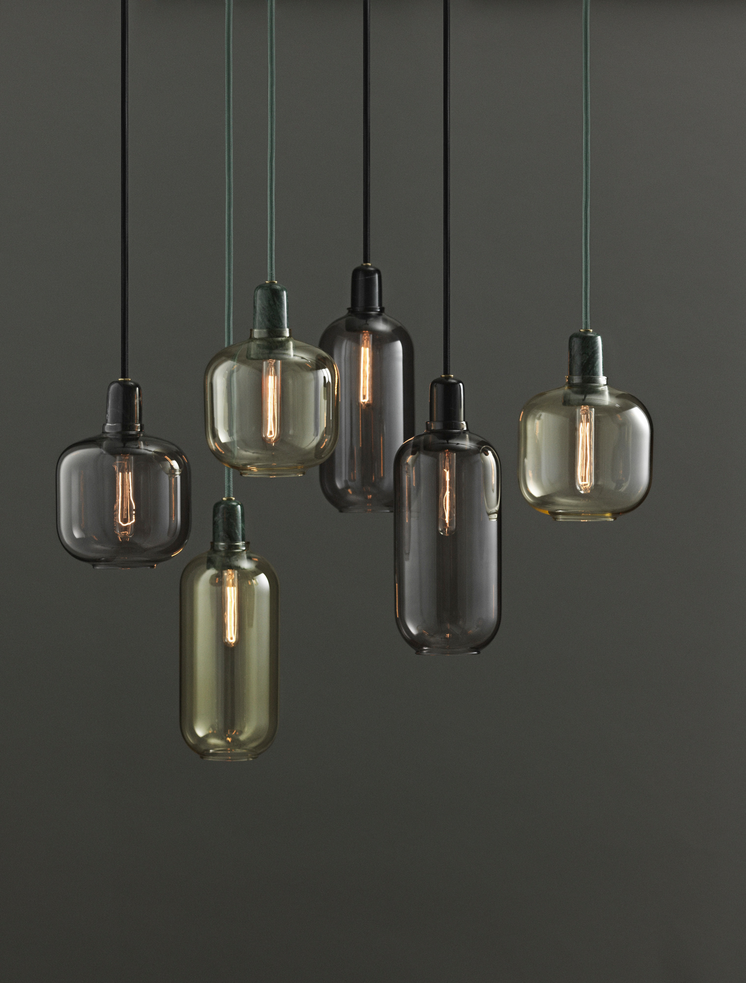 Nahaufnahme von sechs Amp Lamp Hängeleuchten von Normann Copenhagen in Gold und Grün.