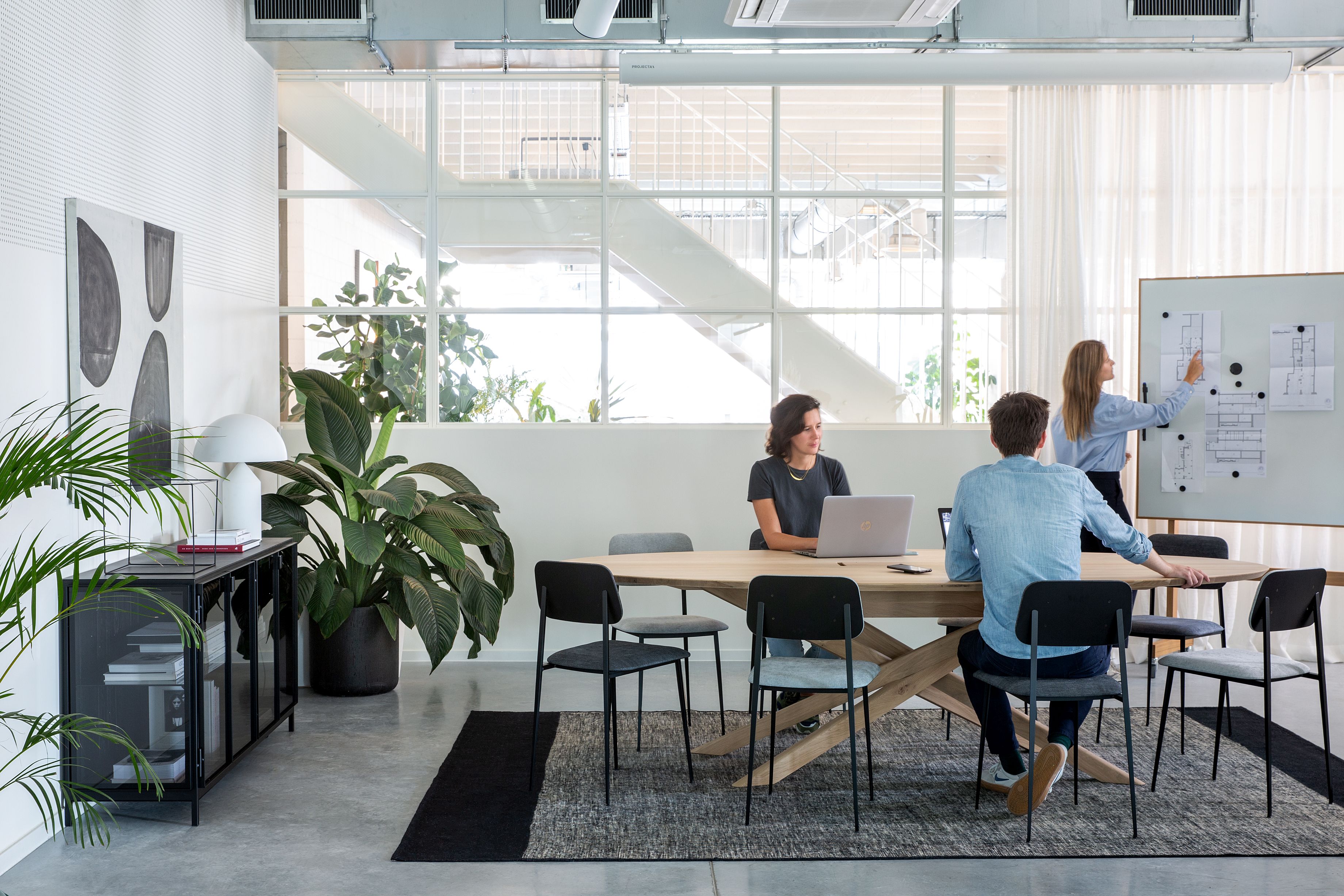 Mikado Meetingtisch Eiche lackiert von Ethnicraft in modernem Büro mit Personen in Besprechung.