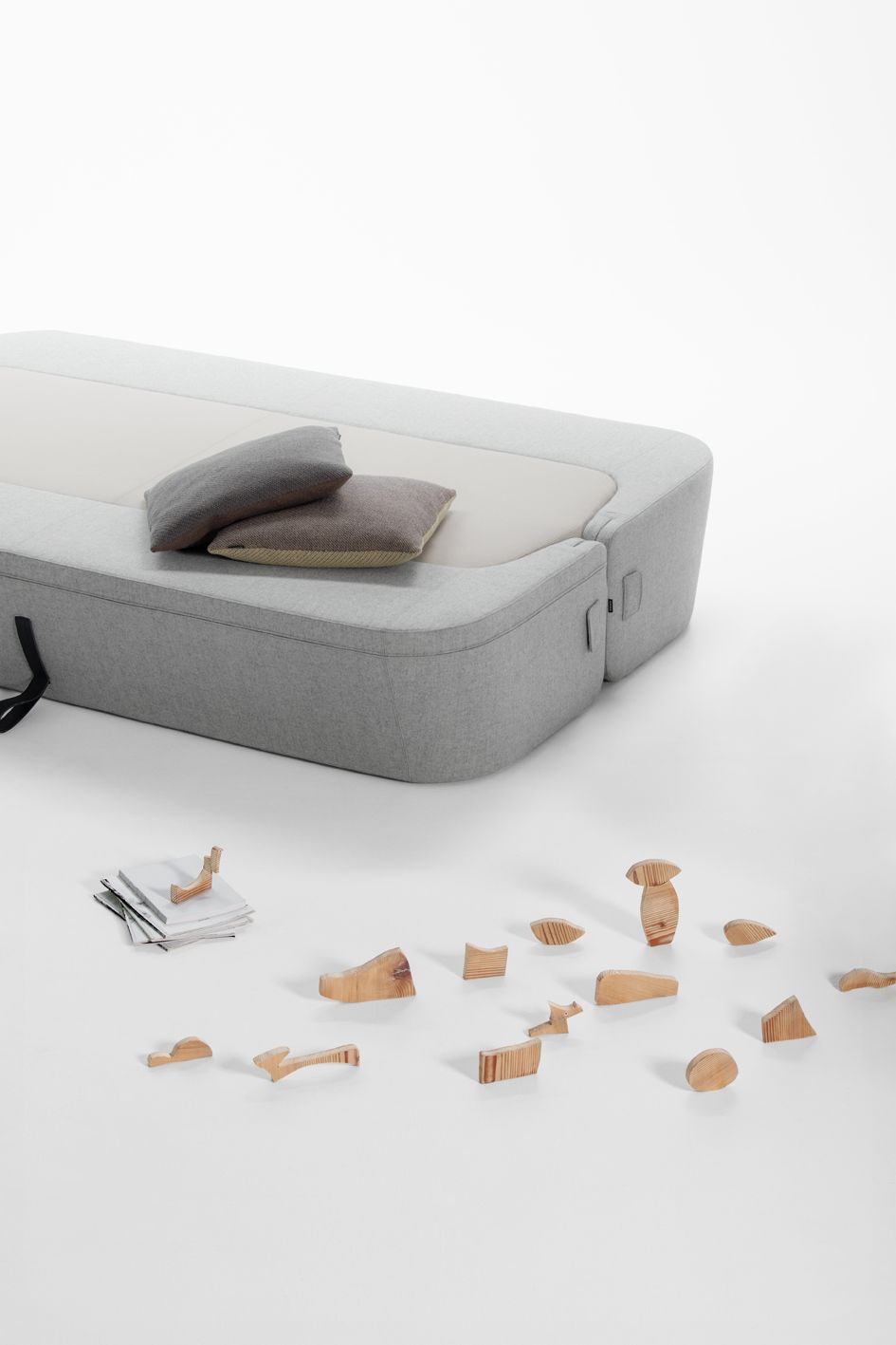 Graues Revolve Schlafsofa von Prostoria mit Kissen und Holzspielzeug auf weißem Hintergrund, ideal für Kinderzimmer.