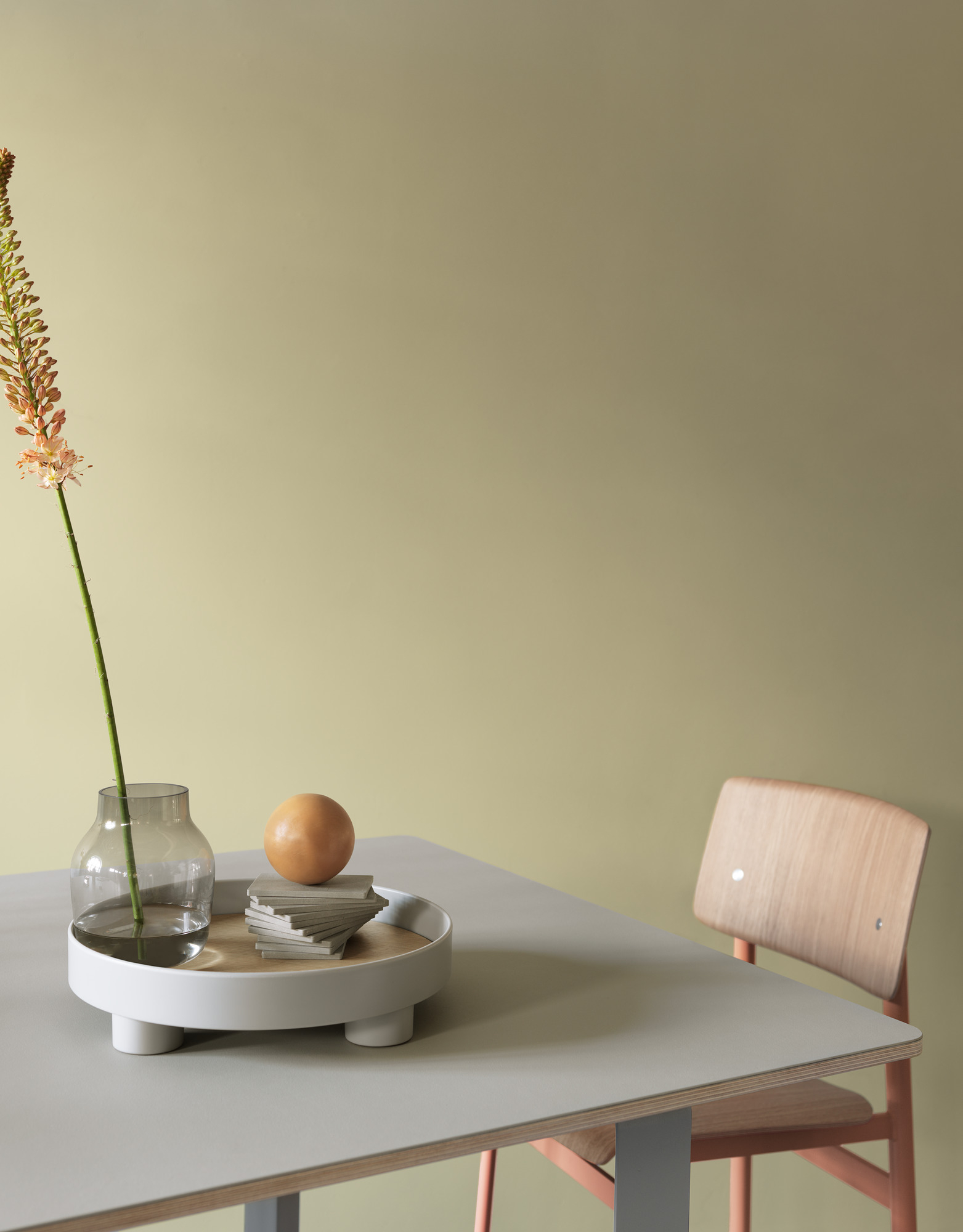 Muuto 70/70 Table Tisch 170x85 cm mit Vase, Deko-Objekten und Stuhl vor hellgrünem Hintergrund.