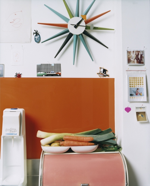 Mehrfarbige Sunburst Clock Wanduhr von Vitra im Retro-Design an einer weißen Wand mit Dekoration.