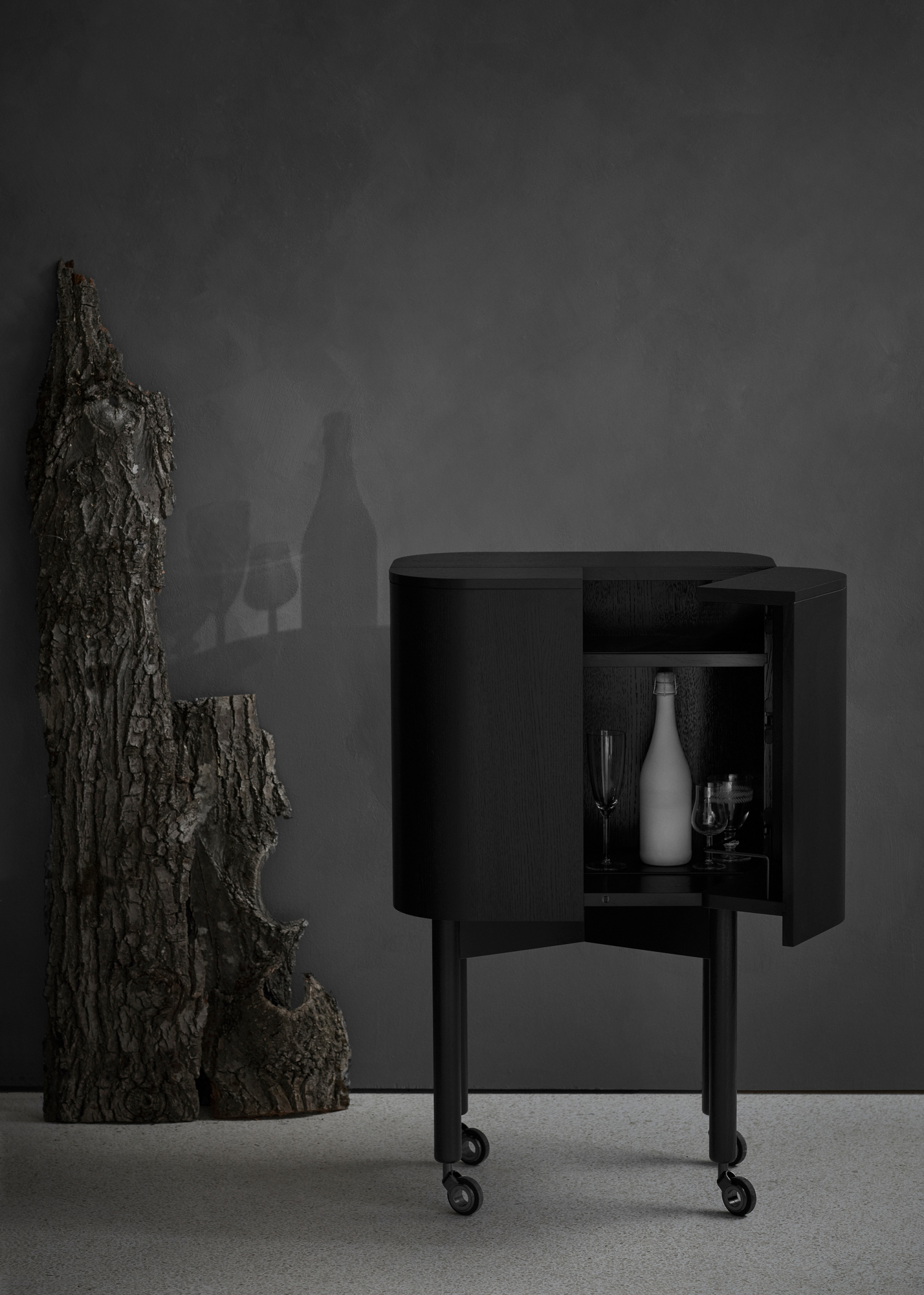 Schwarzer Loud Bar Cabinet Barschrank von Northern mit geöffneter Tür, Flasche und Gläsern auf Rollen.