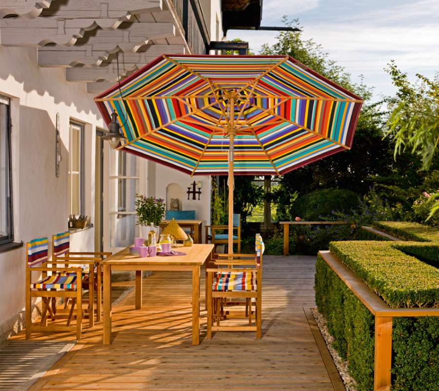 Cabin Sessel von Weishäupl aus Tanne mit farbenfrohen Streifen auf Terrasse mit Gartentisch.