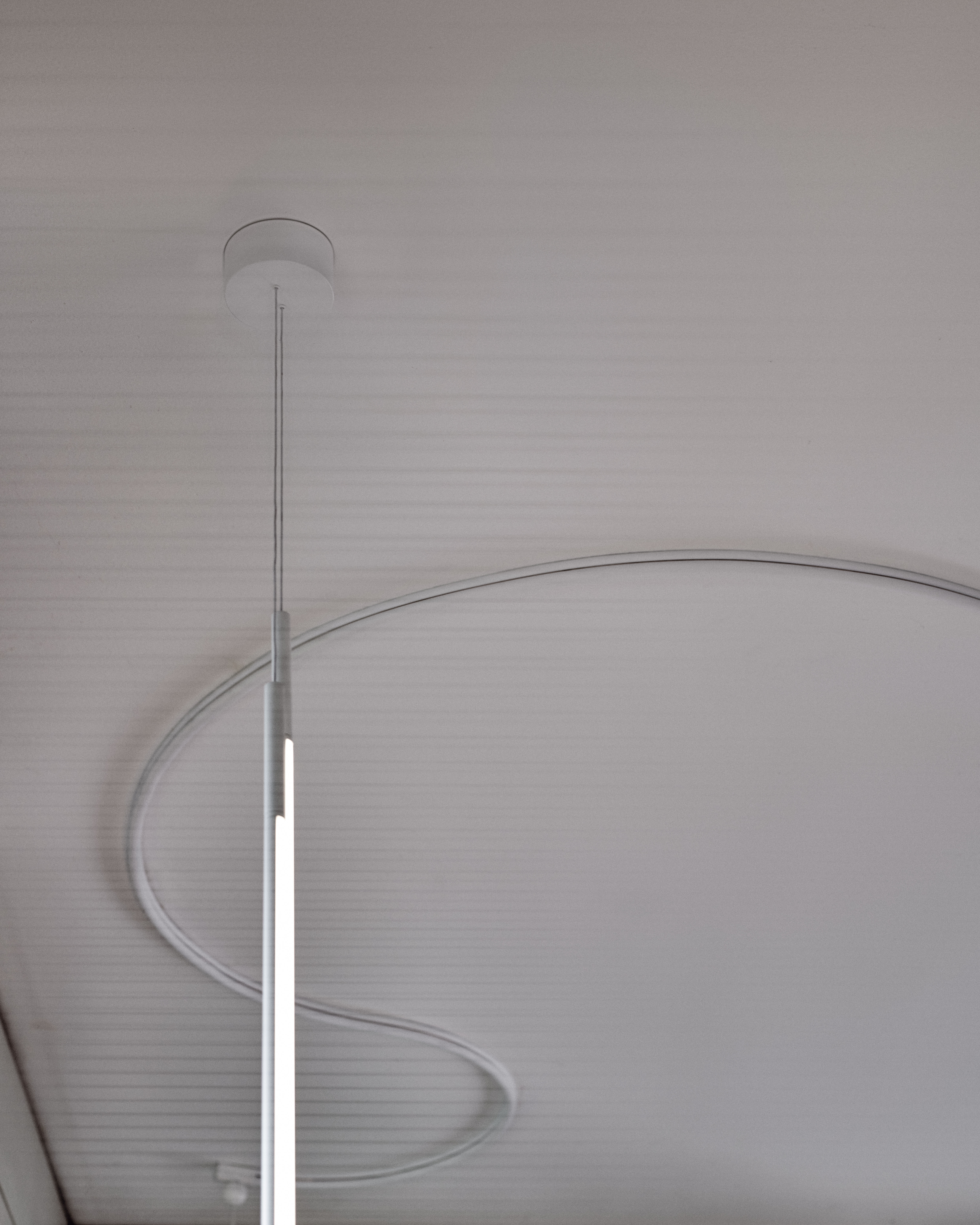 Nahaufnahme der modernen, weißen My Lines Hängeleuchte von Flos an einer Decke.