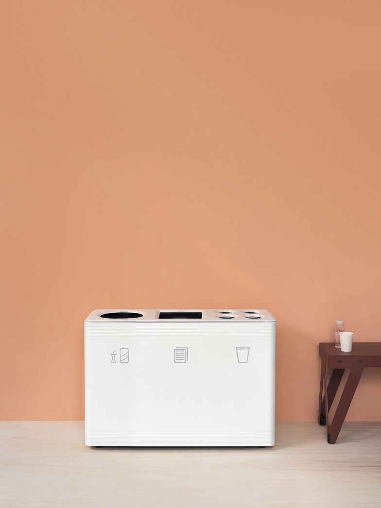 Weißes Ditch 3 Abfalltrennsystem Functionals für Papier, Wertstoffe und Restmüll vor orangefarbener Wand.