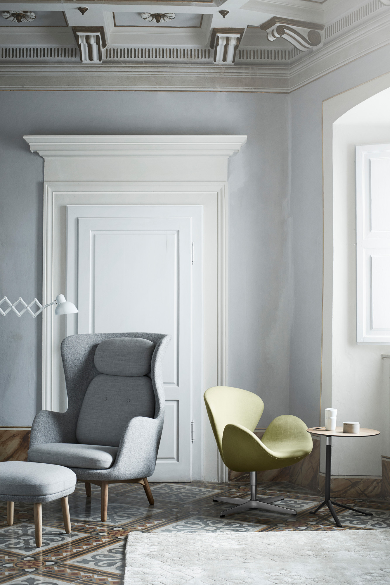 Wohnzimmer Interieur mit Fritz Hansen Sesseln, Beistelltisch, KAISER idell Scherenleuchte und dekorativem Stuck an der Decke.