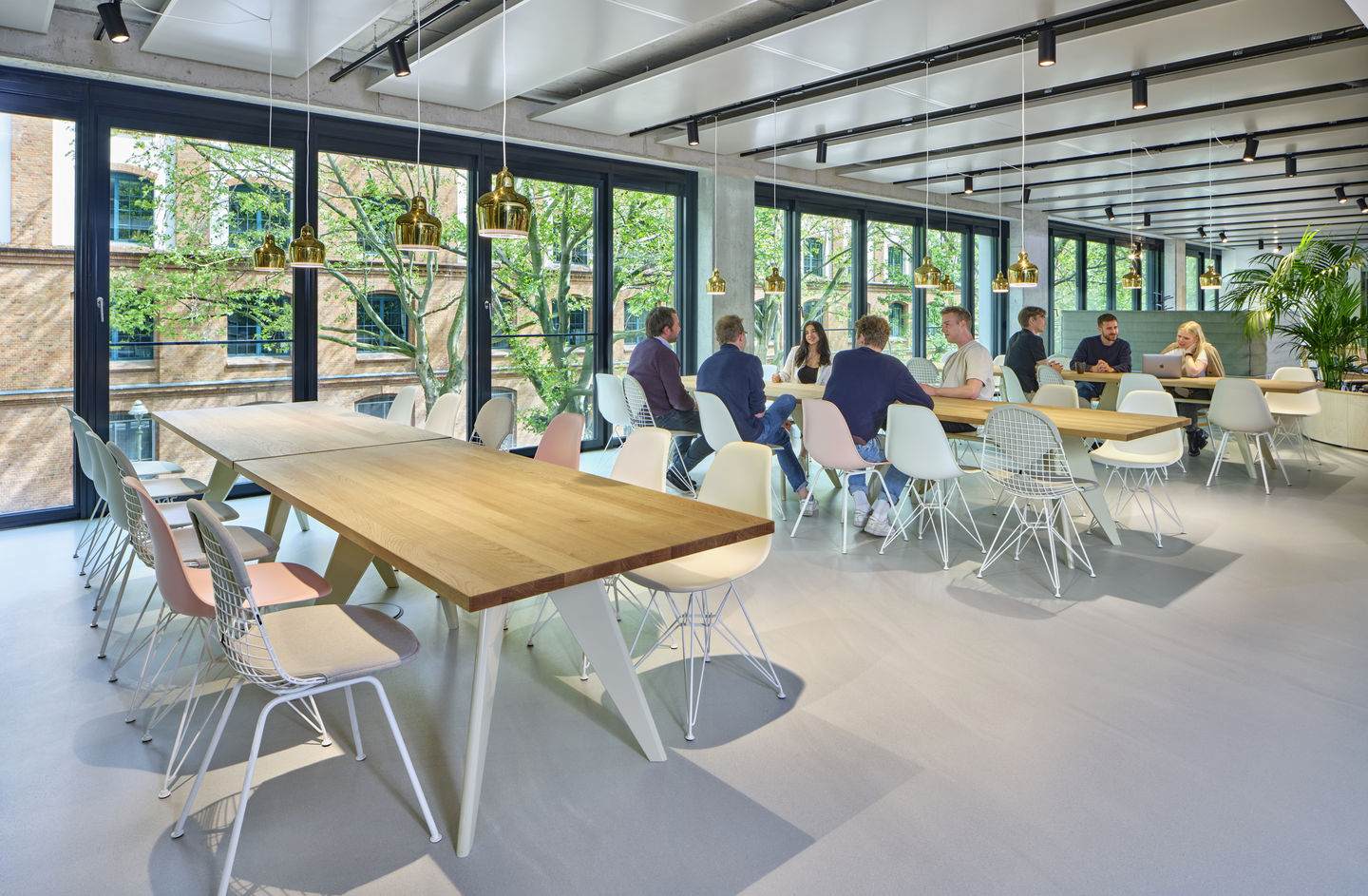 DKX-2 Wire Chair Stuhl von Vitra in einem modernen Büro mit Menschen an Tischen.