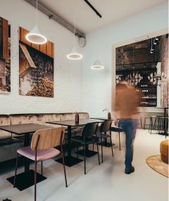 Helle, moderne Annular Pendelleuchte von Woud in einem stilvollen Restaurant, mit sanftem, indirektem Licht.