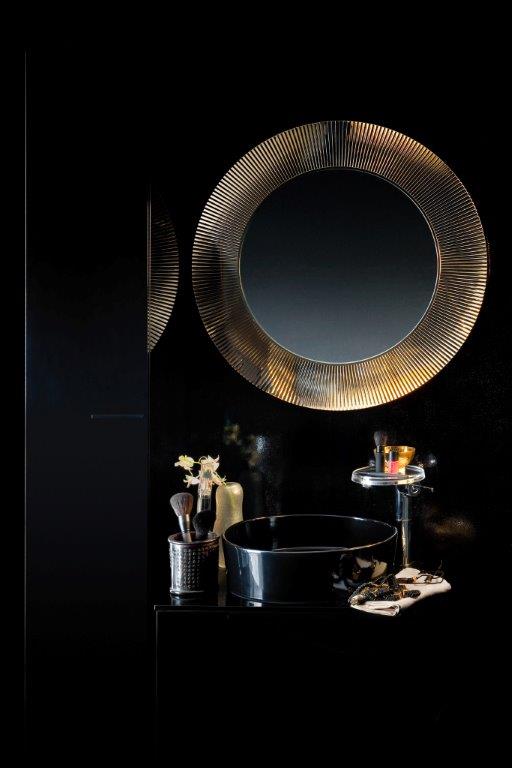 Runder All Saints Spiegel von Kartell mit goldenem Rahmen über einem schwarzen Waschbecken.