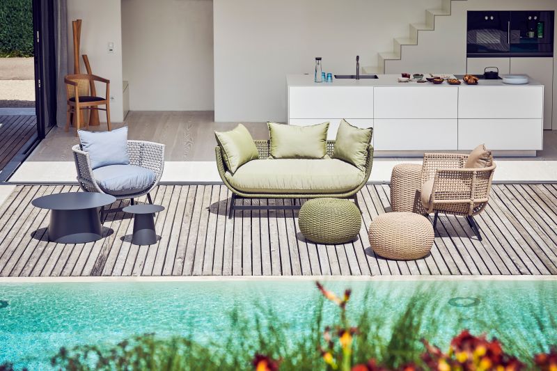 Olivefarbener Jan Kurtz Suka Lounge Sessel und Outdoor-Möbel-Set auf einer Holzterrasse am Pool.
