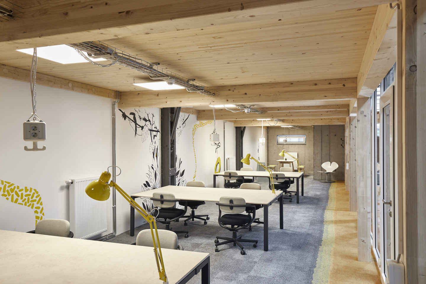 Helles Büro mit mehreren Allstar Bürodrehstühlen von Vitra und gelben Schreibtischlampen an Holztischen.