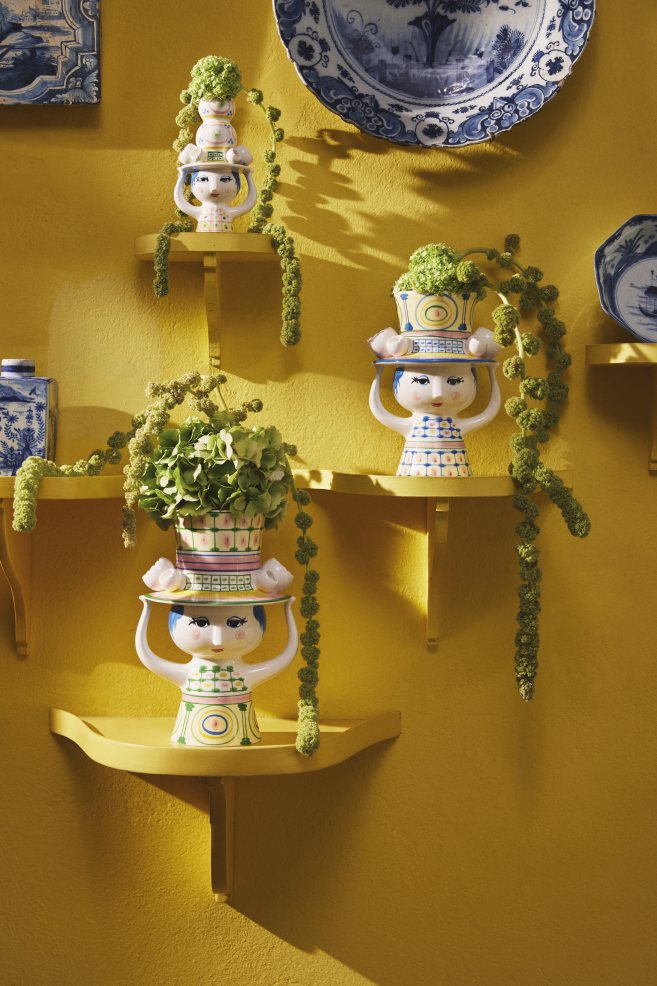 Drei Bjorn Wiinblad Lady with Hat Kerzenständer auf gelben Regalen mit Pflanzen in Hüten.