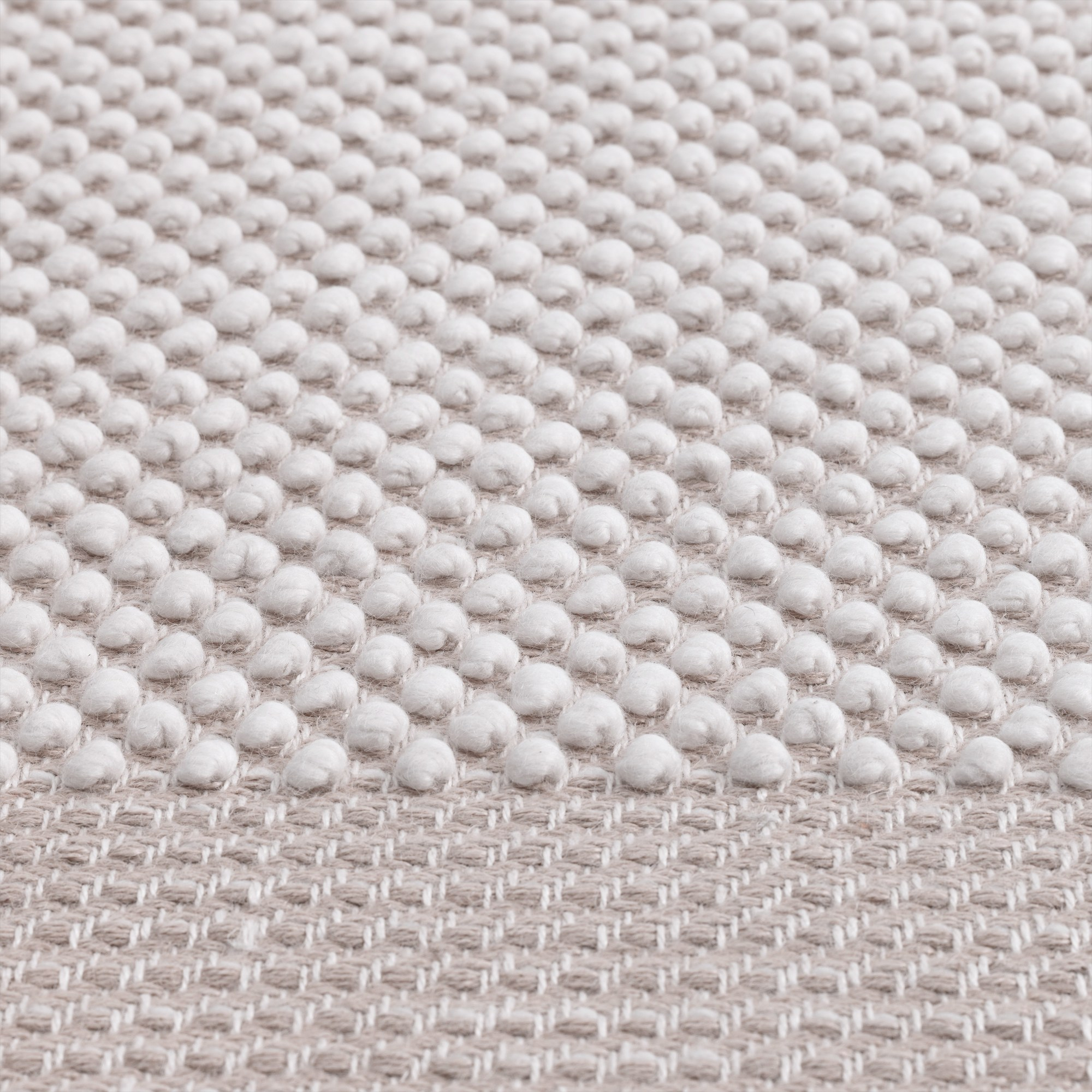 Detailaufnahme des Muuto Pebble Rug Teppichs in Beige, der eine strukturierte Oberfläche mit kleinen Noppen zeigt.