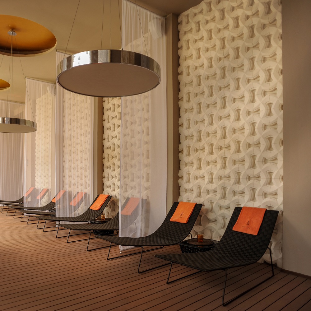 Reihe Trenza Outdoor Liegen von Andreu World mit orangefarbenen Handtüchern auf einer Holzterrasse.