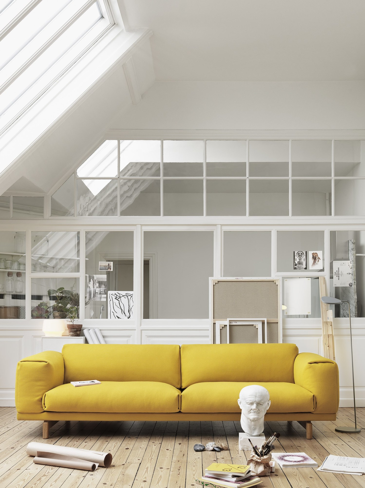 Helle Wohnzimmer-Szene mit gelbem Sofa und grauer Leaf Floor Lamp Stehleuchte von Muuto im Hintergrund.