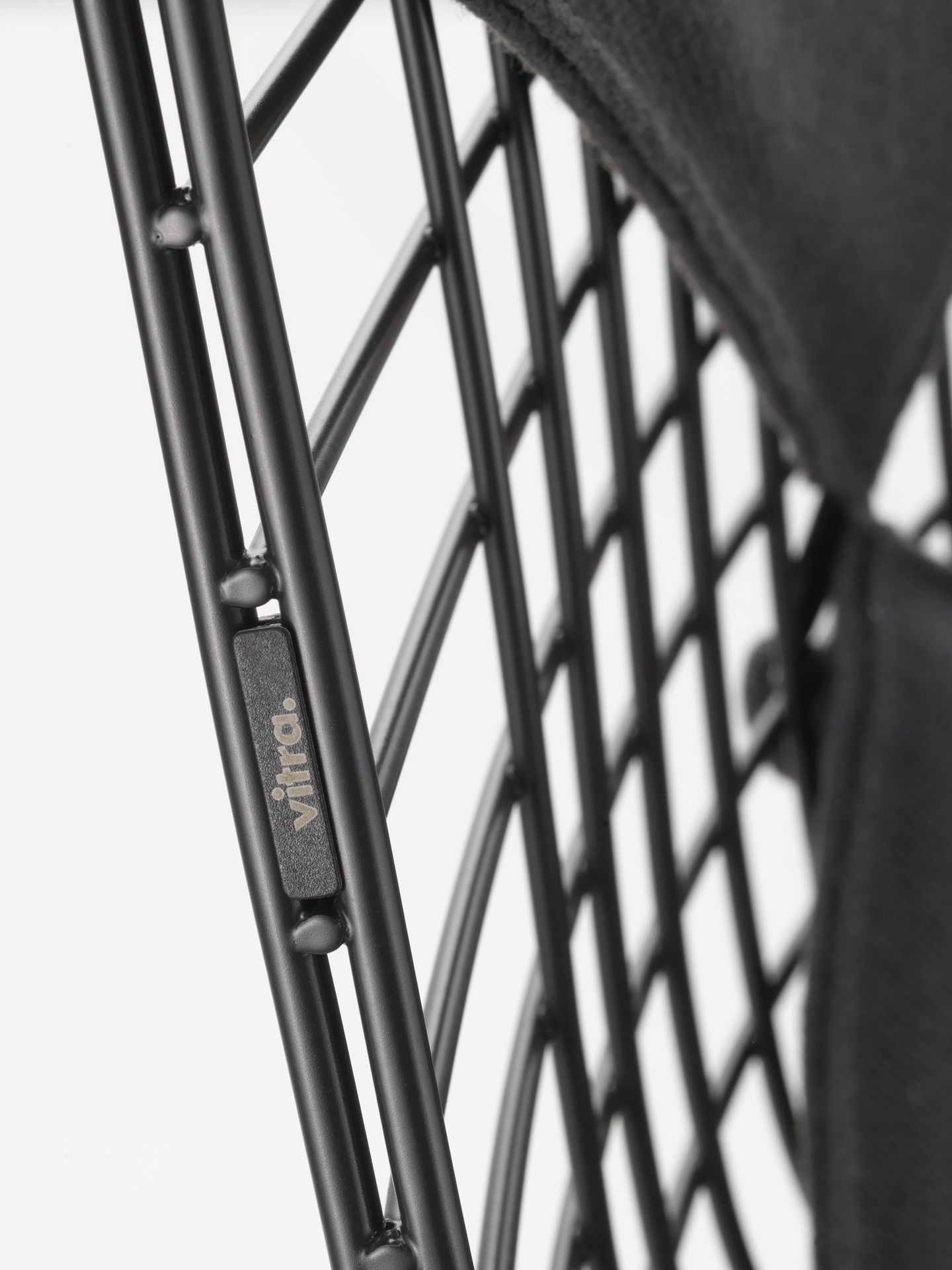 Detailaufnahme des Vitra DKR Wire Chair Stuhls mit schwarzem Sitzpolster und filigranem Drahtgestell.