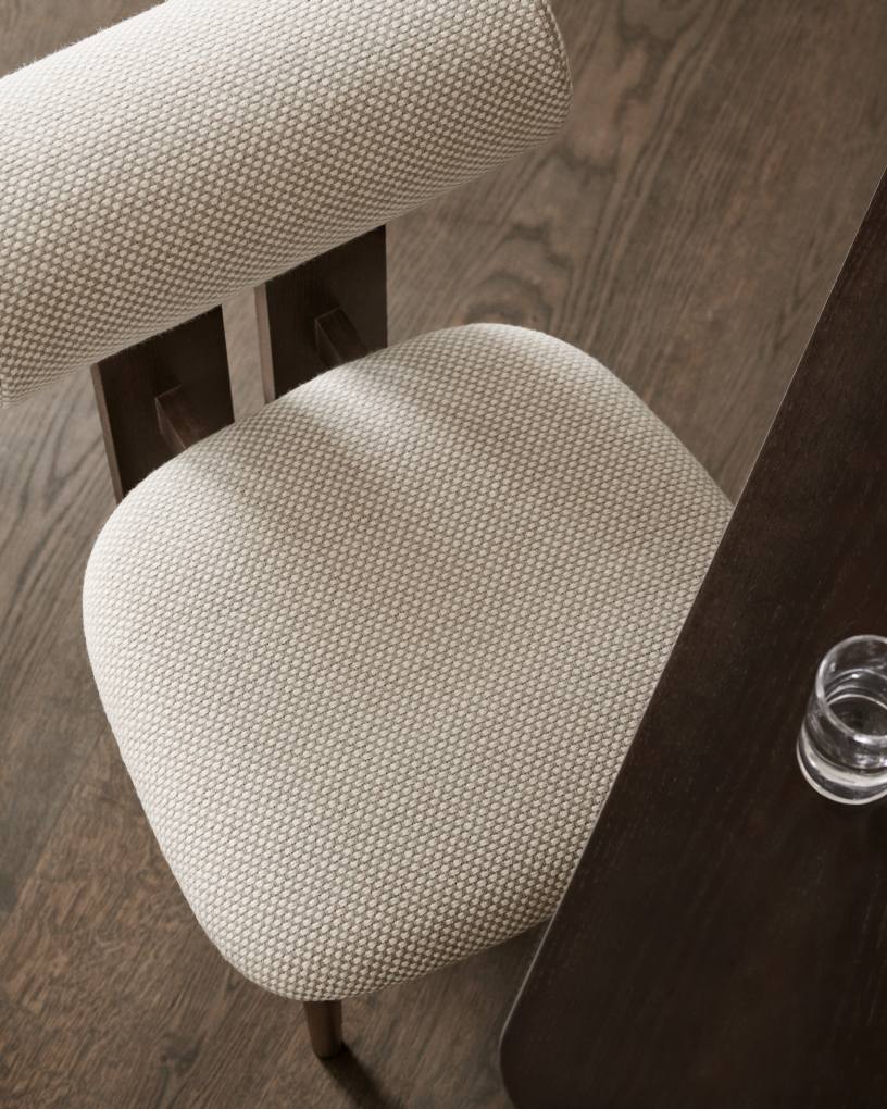 Detailaufnahme des Hippo Stuhls von NORR11 mit hellgrauem Stoffbezug und dunklem Holzgestell, moderne Möbel für Esszimmer.