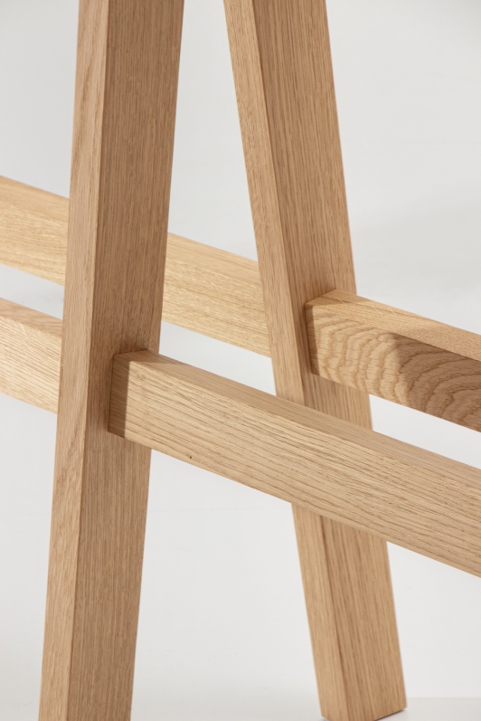 Detailaufnahme der Holzbeine des Cena High Bank Hockers, helle Holzstruktur, minimalistisches Design.