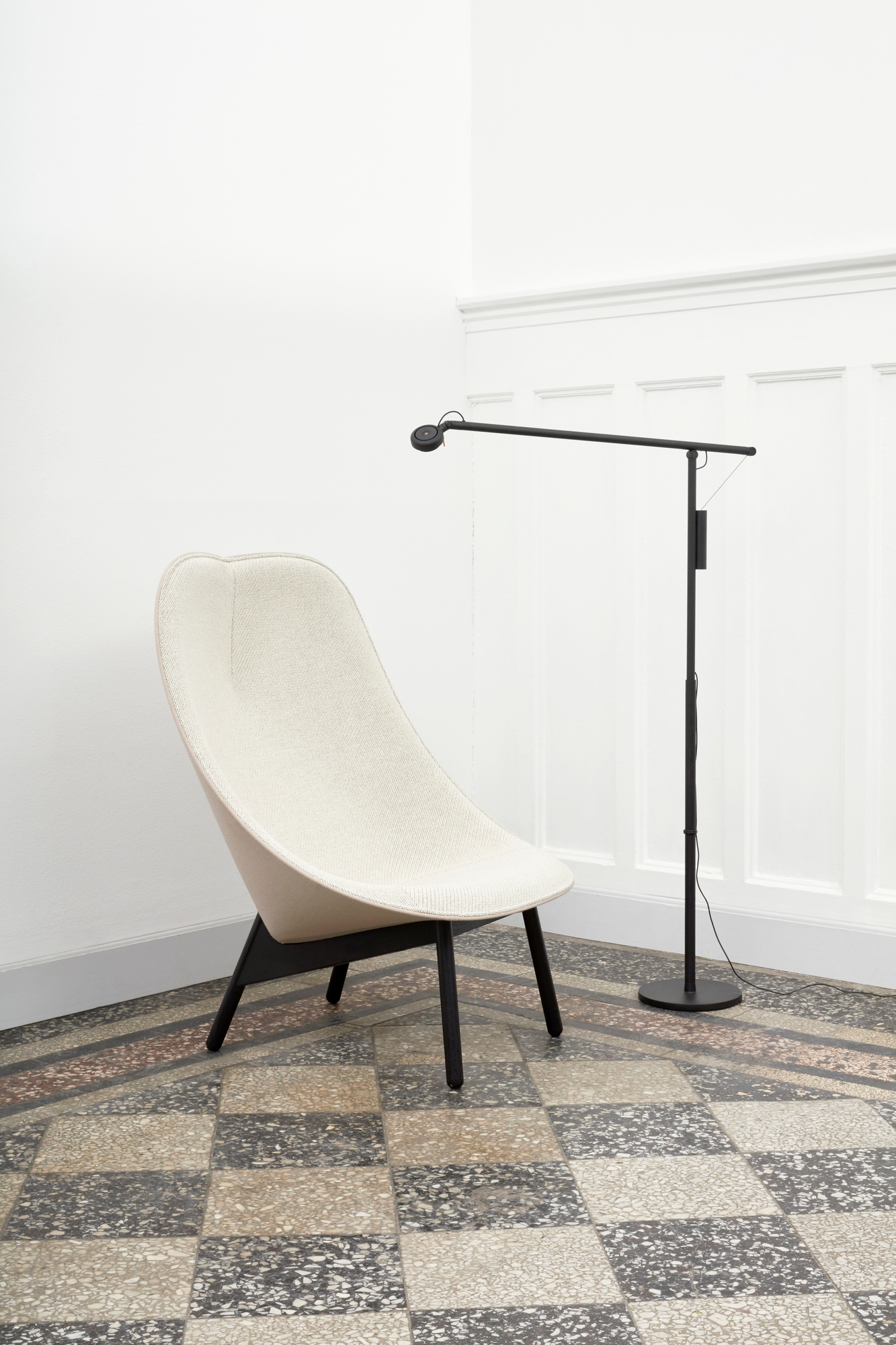 Uchiwa Sessel von Hay, gepolstert mit cremefarbenem Stoff und schwarzem Holzgestell, neben einer Stehlampe.