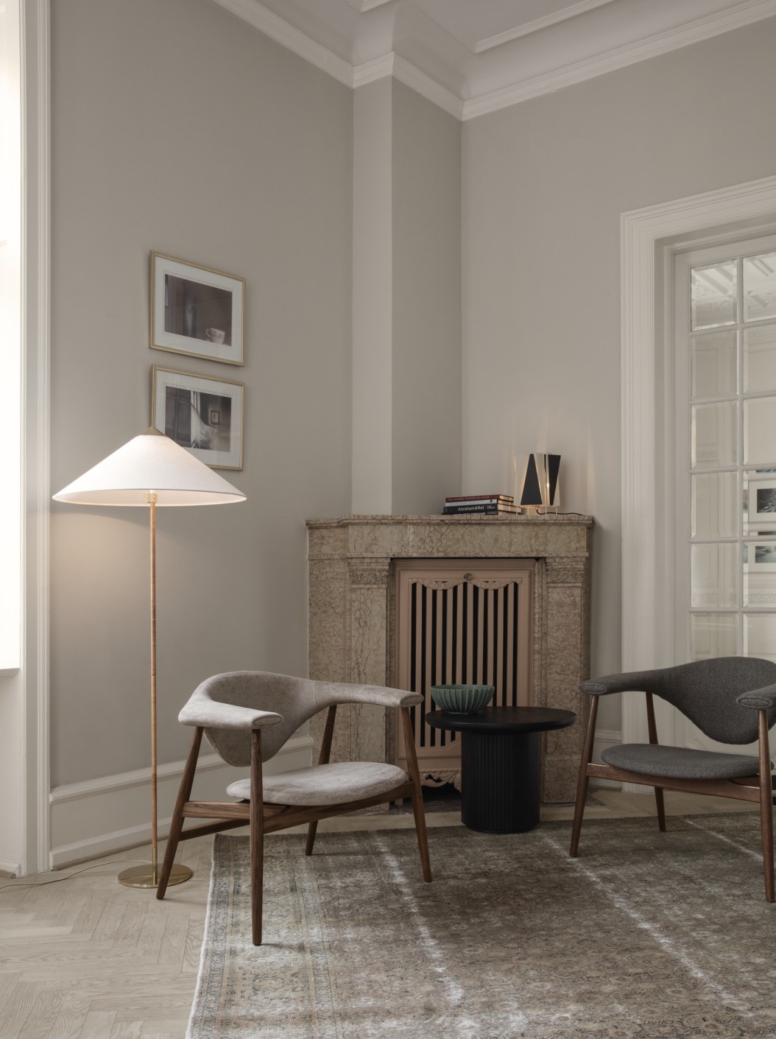 Wohnzimmer mit Gubi Couchtisch Moon Coffee Table 60, Sesseln, Teppich und Kamin.