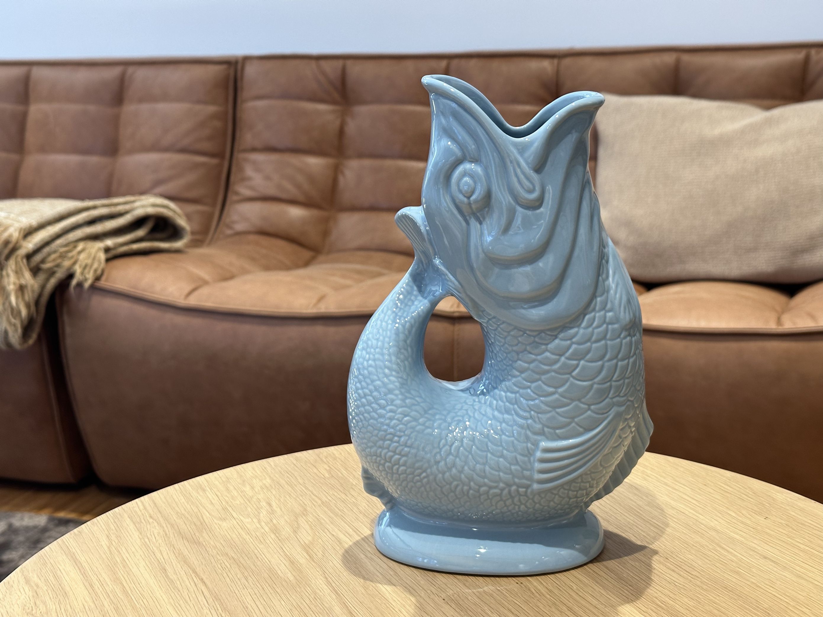 Hellblaue Gluckigluck Fischkaraffe XL auf einem Holztisch, dekorative Wasserkaraffe und Vase.