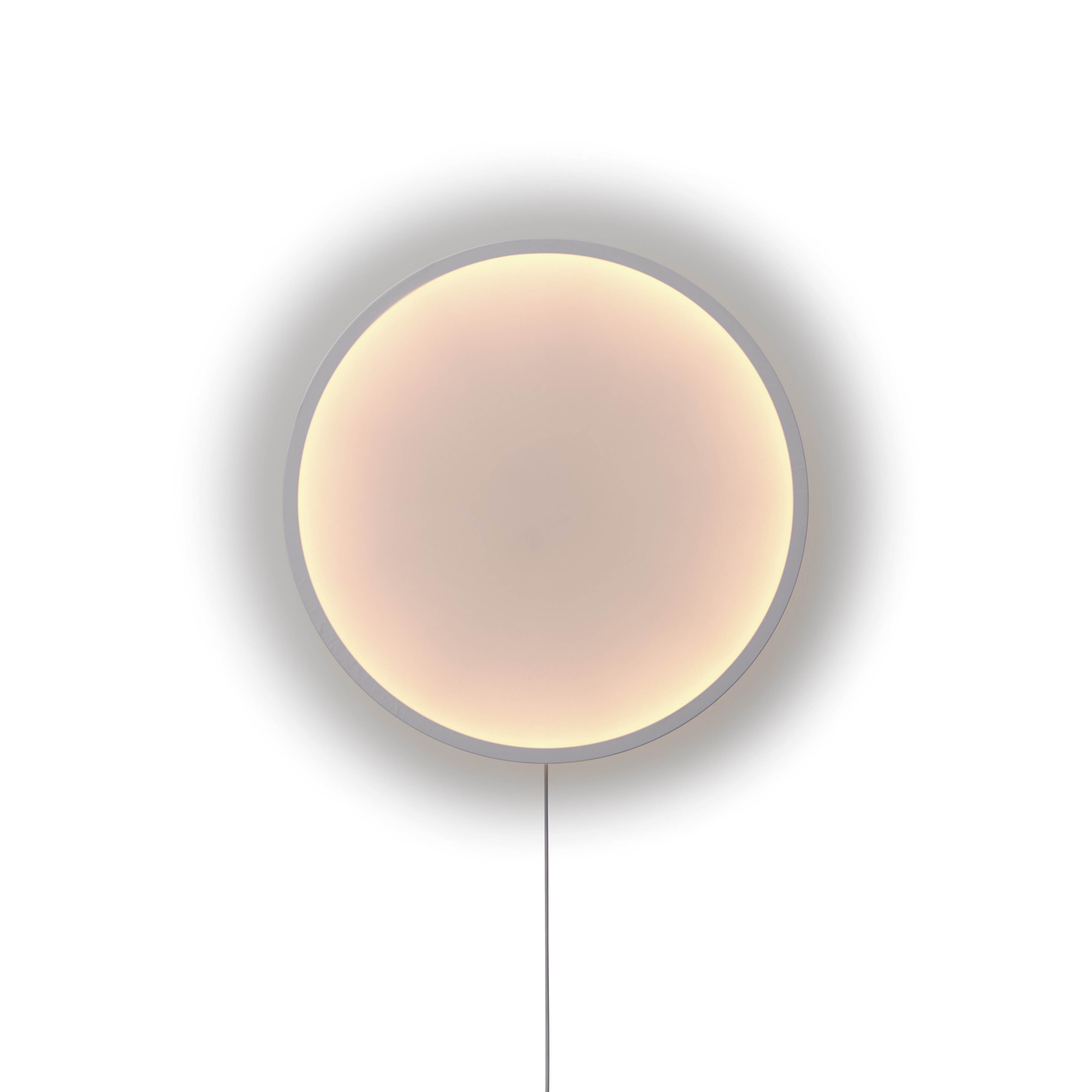 Nahaufnahme der runden Calm Wandleuchte von Muuto mit sanftem, warmem Licht und Kabel.