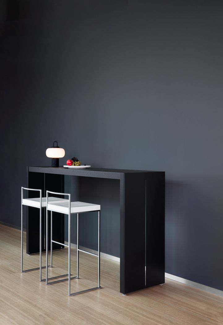 Cubo Barhocker La Palma vor einer dunklen Bar, minimalistisches Design mit weißer Sitzfläche.