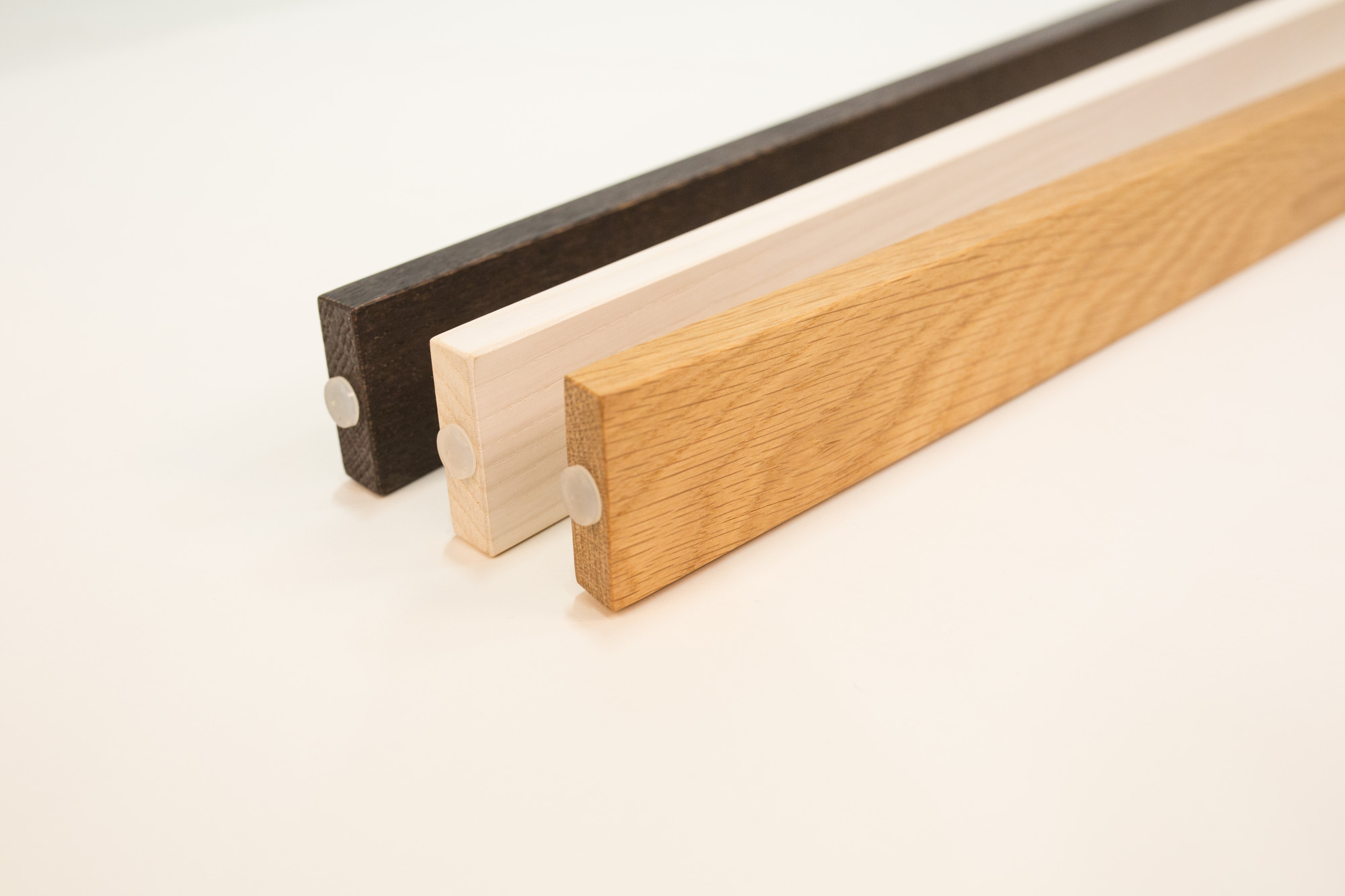 Detailaufnahme von drei Holzfüßen für die Maigrau Luca Stand Stehleuchte in verschiedenen Farben.