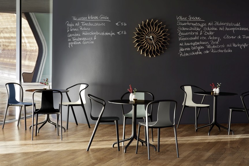 Vitra Belleville Table Tisch mit Stühlen in einem Restaurant mit Speisekarte an der Wand.