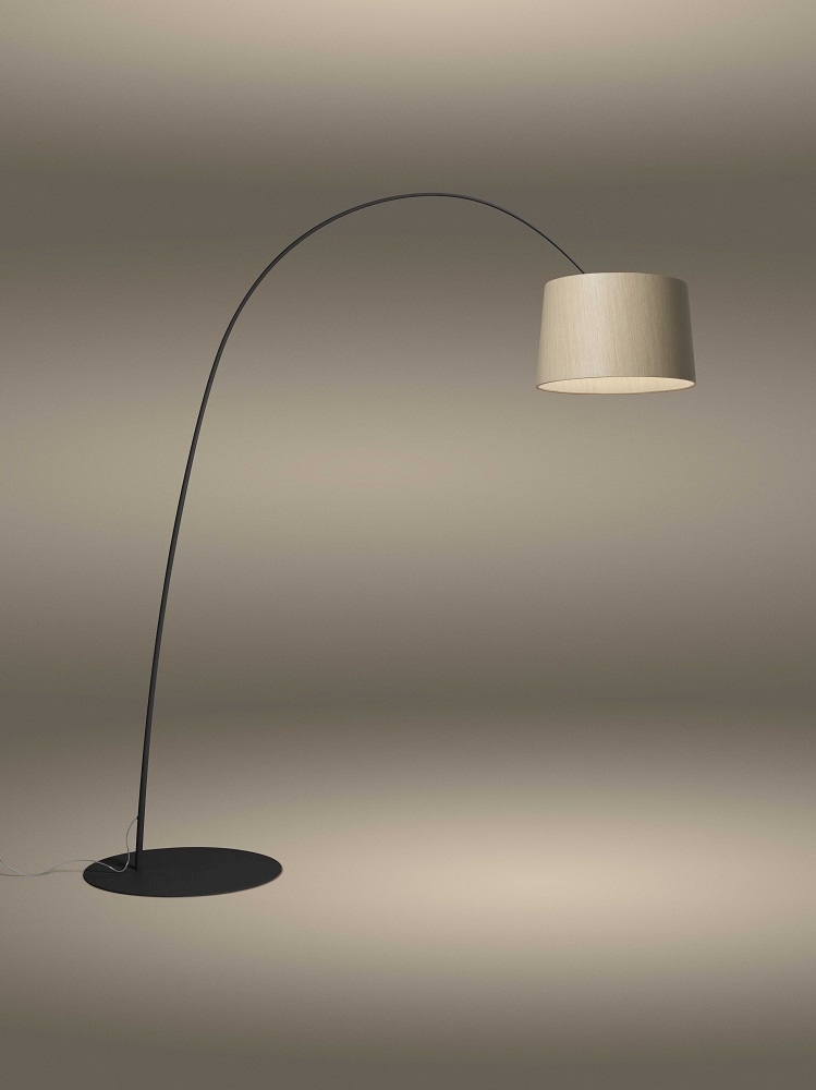 Twiggy Wood Stehleuchte von Foscarini mit gebogenem, schwarzem Lampenfuß und hellem Holzschirm.