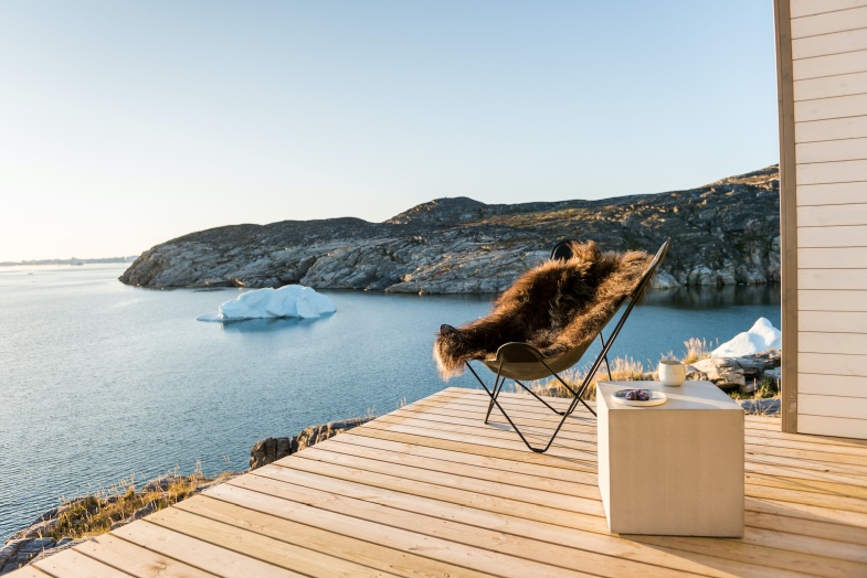 Pampa Mariposa Sessel mit Fell auf Holzterrasse vor arktischer Landschaft. Designmöbel für Wohnen.