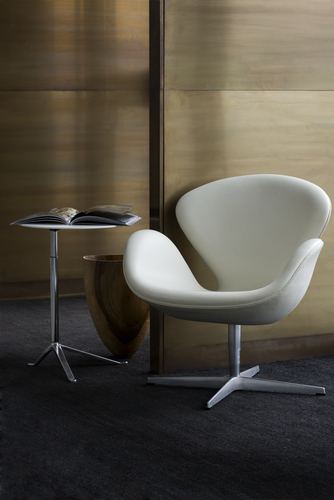 Beiger Schwan Sessel von Fritz Hansen mit Dreifuß-Gestell, Beistelltisch und Holzvase auf dunklem Teppich.