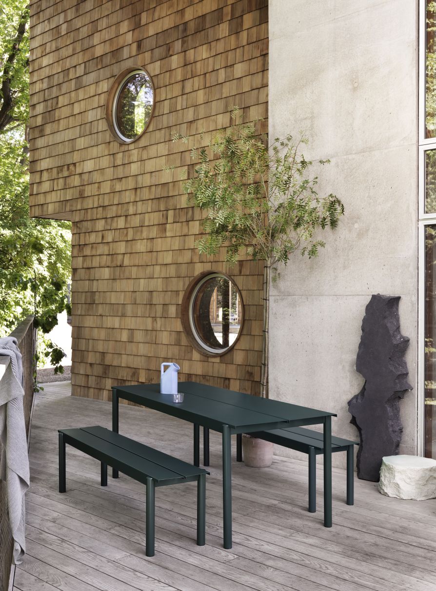 Grauer Linear Steel Outdoor Tisch von Muuto mit zwei Bänken auf einer Holzterrasse.
