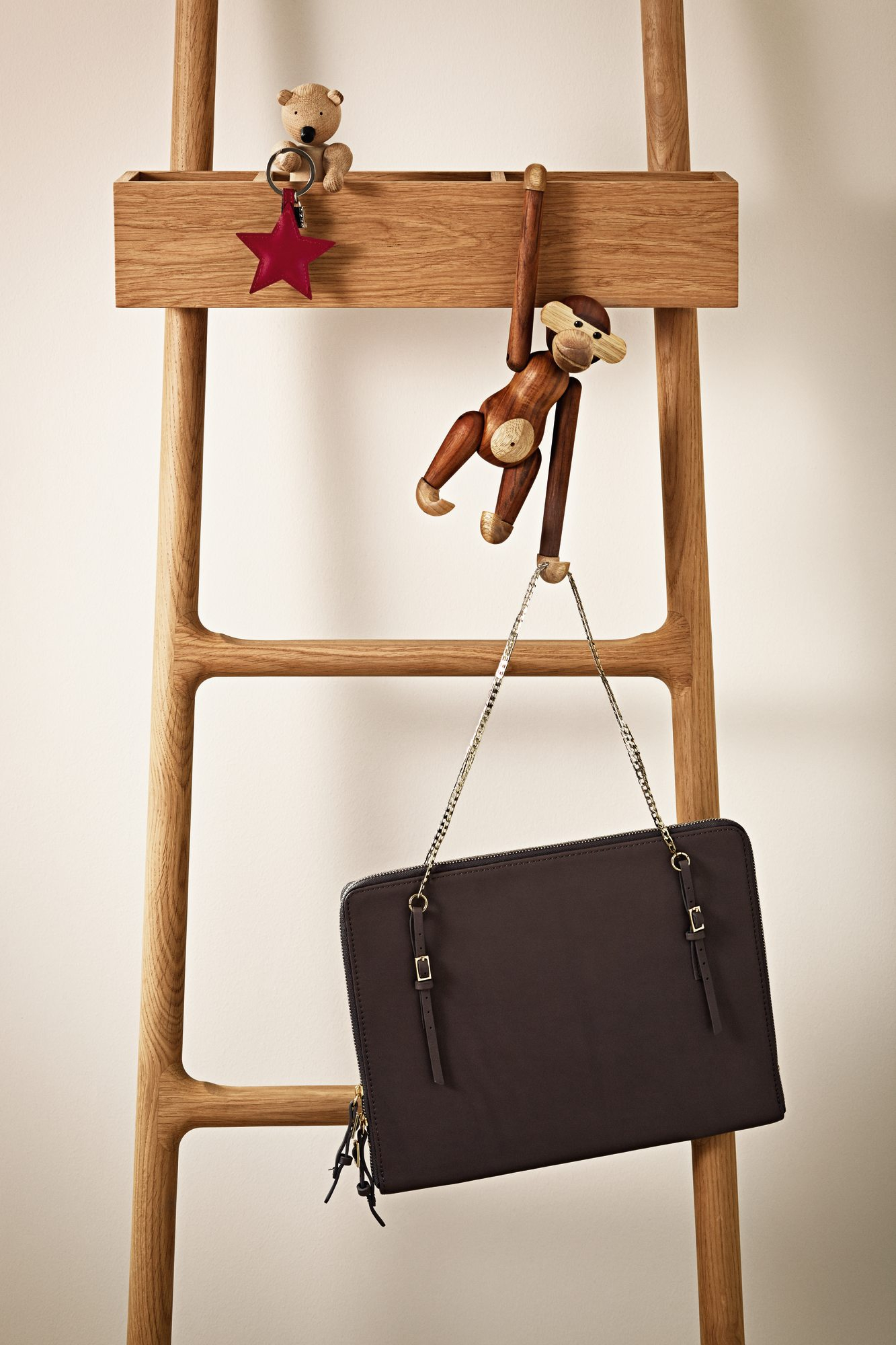 Kay Bojesen Affe Holzfigur aus Teakholz hängt an Holzleiter mit Tasche und kleinem Teddy.