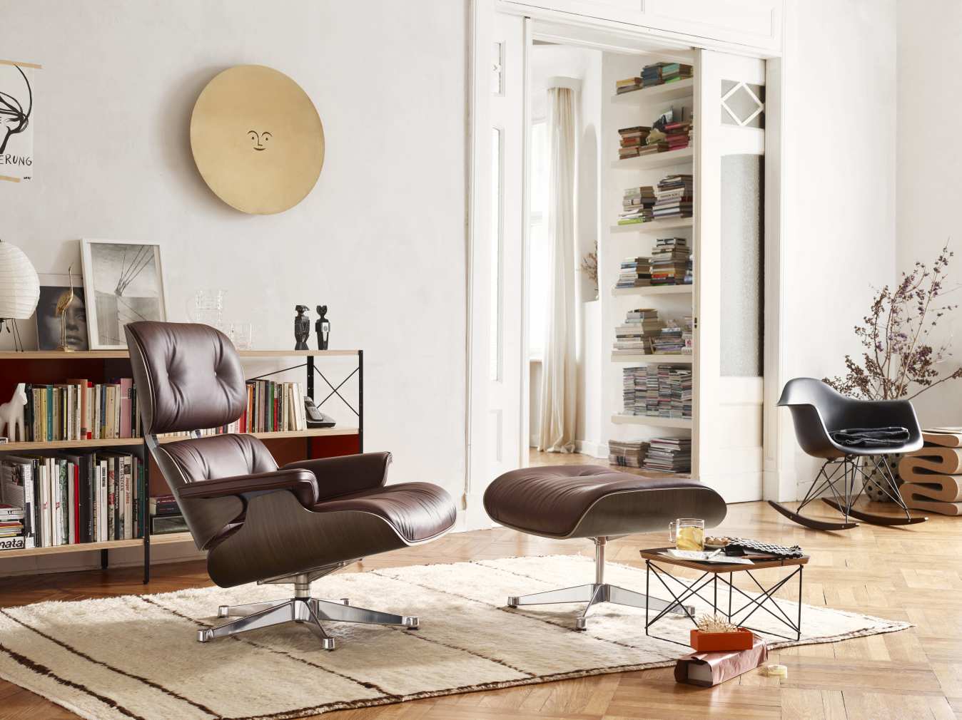 Brauner Eames Lounge Chair Sessel mit Hocker von Vitra in stilvollem Wohnzimmer Ambiente.