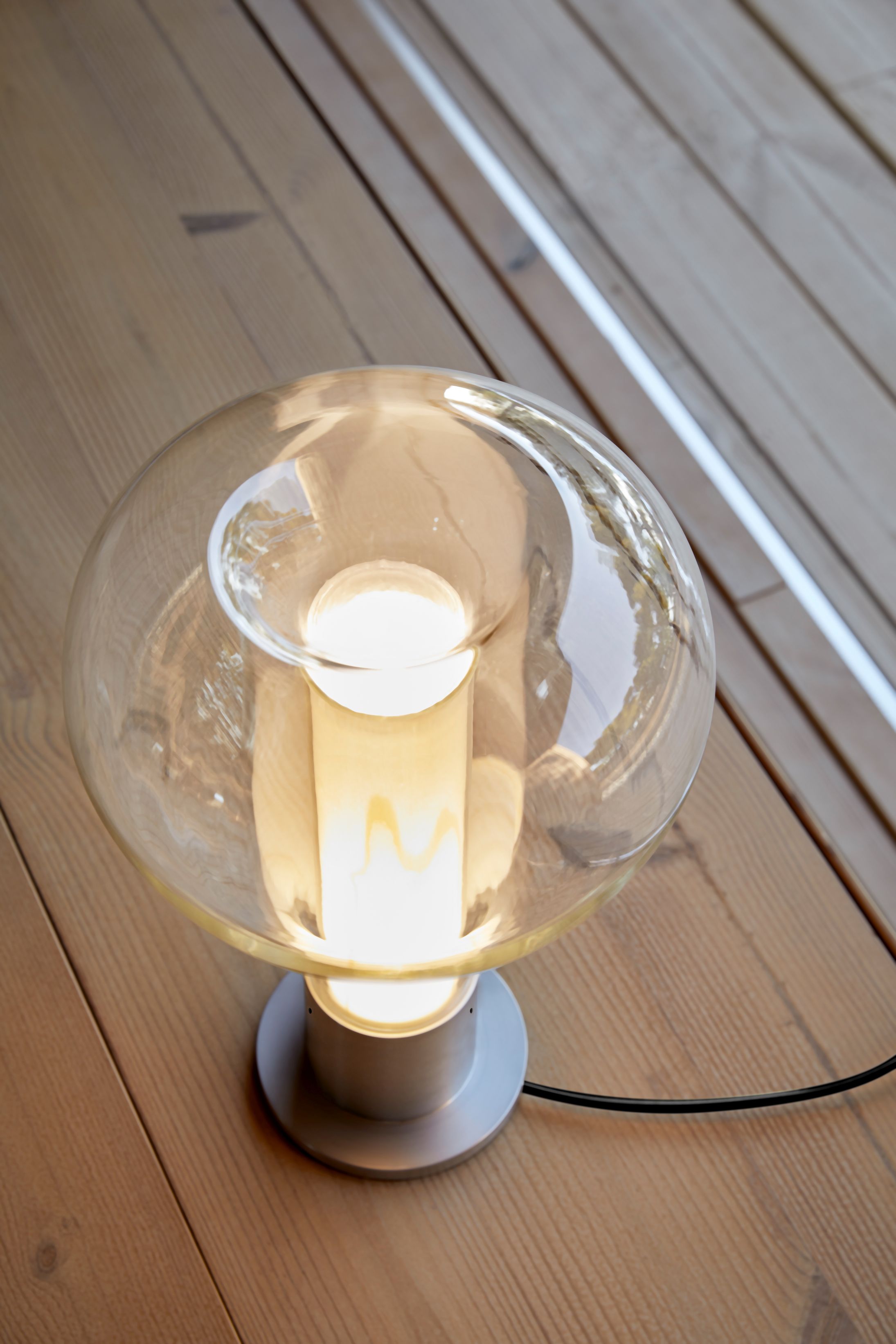 Eris Tischleuchte von LZF Lamps mit Aluminiumsockel und hellrosa Glasschirm, warmes Licht.